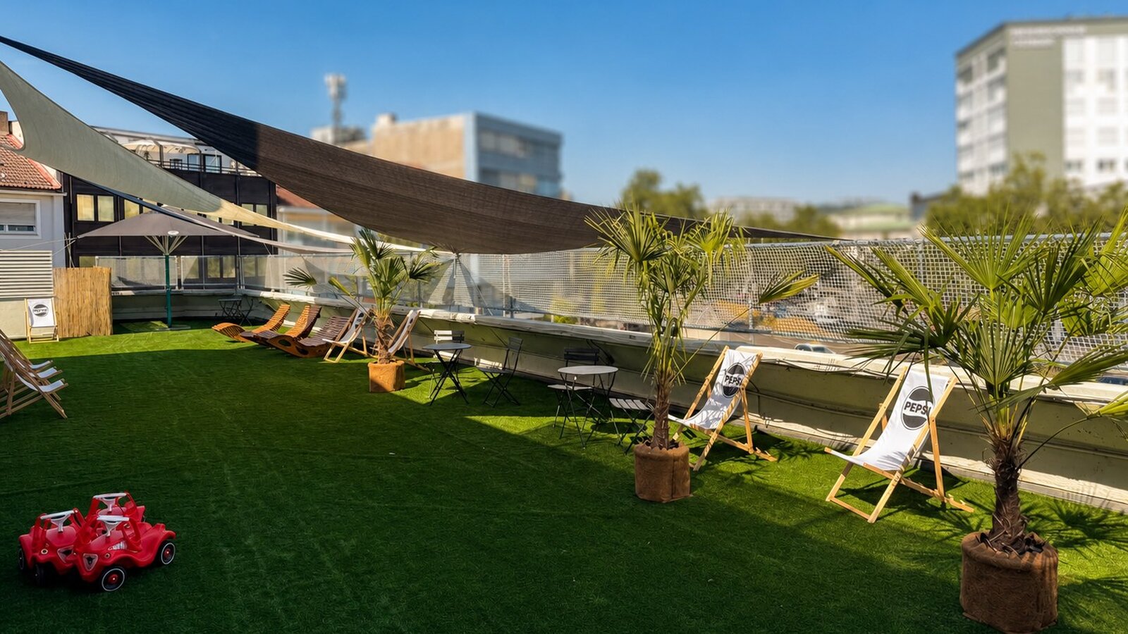 Sonnige Dachterrasse der Play Zone mit Palmen, Liegestühlen und Sitzplätzen